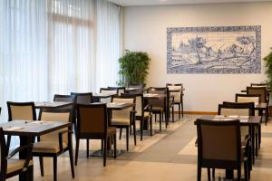 a dining room with tables and chairs and a painting on the wall at TRYP by Wyndham Porto Centro Hotel in Porto