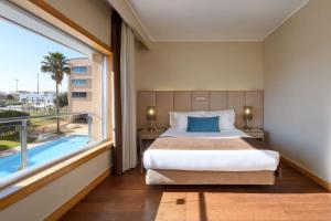 a bedroom with a bed and a large window at TRYP by Wyndham Porto Expo Hotel in Leça da Palmeira