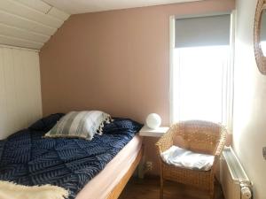 a bedroom with a bed and a chair next to a window at Bard Cottage in Akranes