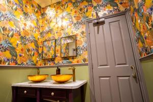 a bathroom with two bowls on a counter with a colorful wall at The Crown Hotel in Glastonbury