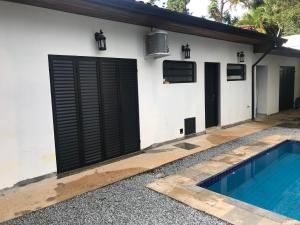 a house with a black garage door and a swimming pool at Colonial Hostel in Sao Paulo