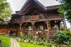 a log cabin with flowers in front of it at Cabana Rustic in Borşa