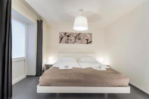 a white bedroom with a large bed with a large window at TGM Hotel Residence in Znojmo