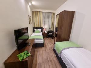 a hotel room with two beds and a flat screen tv at Auenwald Hotel und Apartmenthaus in Leipzig