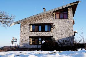 una casa de piedra en la nieve con una escalera en Guest House Daskalov en Chervena Lokva