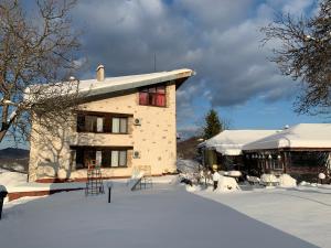 a building with snow on the ground in front of it at Guest House Daskalov in Chervena Lokva
