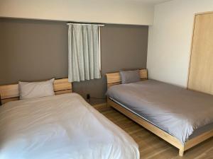 a room with two beds in a room at ホテルトーマスとまり in Naha