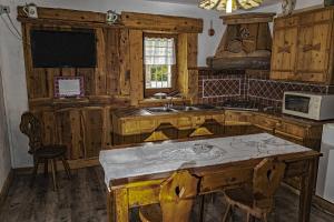 a kitchen with wooden cabinets and a table with a sink at Chèvres à Cheval - Apartment in Aosta