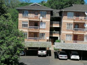 an apartment building with cars parked in a parking lot at ALL SAINTS ON ROBERTS in Pietermaritzburg