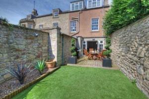 a backyard with a stone wall and a grass yard at Goshen Cottage in Kelso