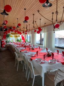 a long banquet hall with red tables and chairs at Guest House Daskalov in Chervena Lokva