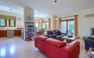 een woonkamer met een rode bank en een keuken bij 3 bedroom Villa Madelini with private pool, Aphrodite Hills Resort in Kouklia