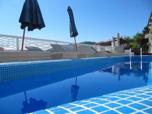 a blue swimming pool with an umbrella and chairs at Relais Bijoux Ischia in Ischia