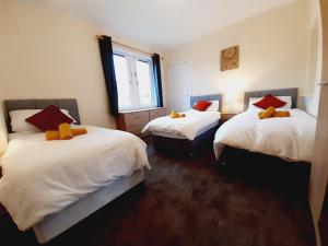 um quarto com duas camas com almofadas vermelhas e amarelas em Carvetii - Vincent House - Large 3 bedroom apartment with on-site parking em Fife