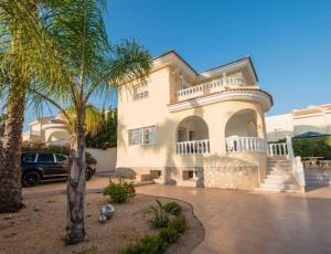 una grande casa bianca con una palma di fronte di Luxury Private Villa Casa JoJo own Pool & Hot tub a Ciudad Quesada