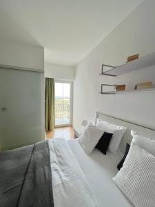 a white bedroom with a large white bed with pillows at Apartment STAR Blažev in Primošten