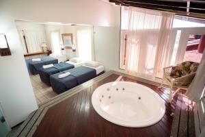 a bathroom with a tub and a living room at Aimberê Eco Resort Hotel in Coqueiro