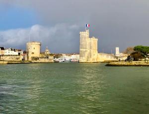 a castle with a flag on top of it next to the water at Nuit insolite sur un voilier au cœur de La Rochelle in La Rochelle