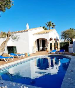 a villa with a swimming pool in front of a house at Villas El Pinar in Cala en Blanes