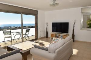a living room with a couch and a flat screen tv at Villa Miramar Panoramic Views in Santa Susanna