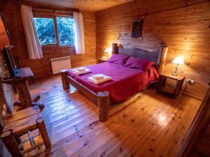 Un dormitorio con una cama en una cabaña de troncos en Hosteria Pichi Rincon, en Villa La Angostura 55 fotos más
