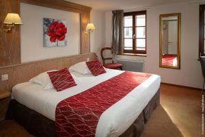 a bedroom with a large bed with red pillows at Logis Hôtel De La Cloche in Obernai +41 photos