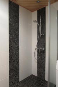 a shower in a bathroom with black and white tiles at Vanamo in Ylläsjärvi