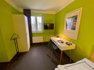 a green room with a desk and a window at Hotel Kaiserswerth in Düsseldorf