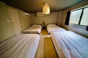 three beds in a small room with a window at 自由自在OSU 202(UMI) in Nagoya