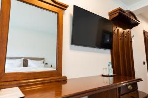 a mirror in a room with a bed and a television at Pensiunea Casa Vera in Târgu Jiu