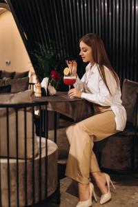 a woman sitting at a table with a drink at Garden plaza in Neresnytsya