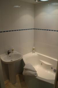 un bagno bianco con vasca e lavandino di Penrith Lodge a Stroud