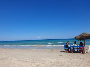 three people sitting at a table on the beach at Mahdia - Baghdadi - Laourient Apartments, restaurant, café in Mahdia