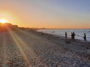 a group of people on the beach at sunset at Mahdia - Baghdadi - Laourient Apartments, restaurant, café in Mahdia