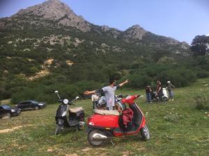 a man standing next to a red scooter in a field at Mahdia - Baghdadi - Laourient Apartments, restaurant, café in Mahdia