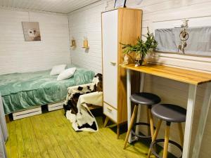 a room with a bed and a desk and stools at Ambarcasa Farm - Дом для уединения in Kalman'