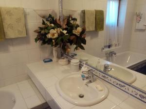 a bathroom with a sink and a vase of flowers at Siusi Sciliar Apartment in Siusi