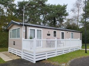a tiny house with a white fence at 5 Geranium, Holiday Home in Oakdene Forest Park in Ferndown