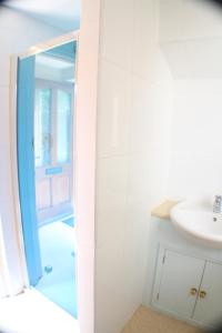 a white bathroom with a sink and a mirror at Penrith Lodge in Stroud