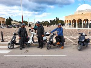 a group of people standing next to scooters in a parking lot at Mahdia - Baghdadi - Laourient Apartments, restaurant, café in Mahdia