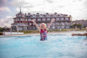 a little girl standing in the water in a pool at Grand Arctic Resort in Överkalix