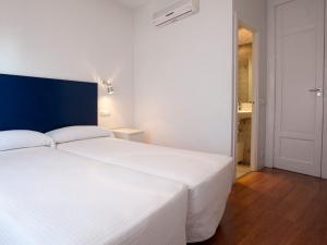 a bedroom with a large white bed with a blue headboard at Hostal Santa Isabel in Madrid