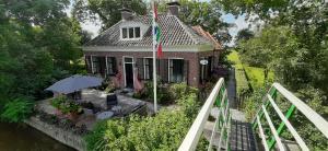 a house with an umbrella on a deck next to a river at B&b Hoogholtje in Onderdendam