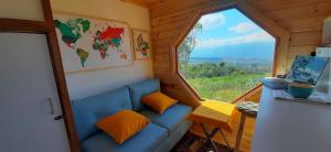 Habitación pequeña con sofá azul y ventana en Mini Casa Barichara, en Barichara