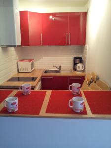 a kitchen with red cabinets and two cups on the counter at Magicappart in Magny-le-Hongre