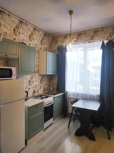 ポルタヴァにあるАпартаменты на Героев-Чернобыльцев 27のキッチン(緑のキャビネット、テーブル、窓付)