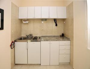 eine Küche mit weißen Schränken und einem Waschbecken in der Unterkunft Studio Stari Grad in Herceg-Novi