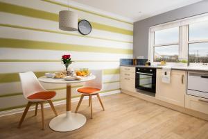 una cocina con paredes de rayas verdes y blancas, mesa y sillas en Bastle Retreats Farm Cottage en Duns
