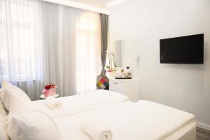 Habitación blanca con 2 camas blancas y TV de pantalla plana. en Plovdiv City Center Hotel en Plovdiv