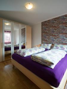 een slaapkamer met een groot bed met een bakstenen muur bij Benkelberg in Sitzerath